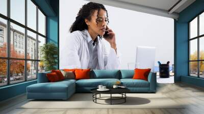 African american mid adult woman talking over smart phone and using laptop on desk, copy space Wall mural