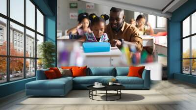 African american young male teacher teaching african american elementary girl on wheelchair in class Wall mural