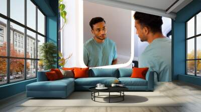 Biracial man looking at himself in bathroom mirror Wall mural