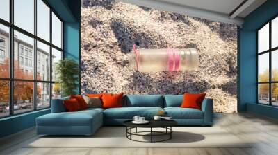 Directly above view of abandoned plastic bottle on white sand at beach during sunny day Wall mural