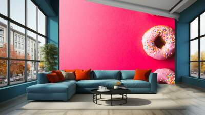 Directly above view of pink donuts with sprinklers arranged by copy space on colored background Wall mural