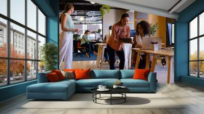 Diverse female colleagues in discussion using tablet in casual office meeting Wall mural