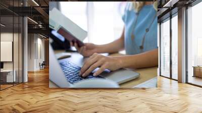 Female executive checking ticket status online over laptop Wall mural