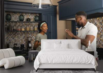 Happy african american couple talking and preparing meal together in kitchen Wall mural