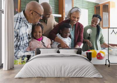 Happy african american multi generation family chopping vegetables in kitchen, slow motion Wall mural