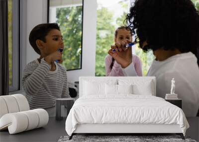 Happy biracial mother, son and daughter brushing teeth together in bathroom in the morning Wall mural