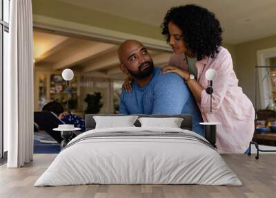 Happy biracial parents using laptop, looking at bills, with daughter in background, copy space Wall mural