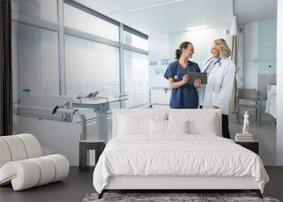 Happy caucasian female doctors with stethoscopes using tablet at hospital, copy space Wall mural