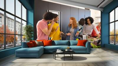 Happy diverse friends cooking together and smiling in kitchen Wall mural