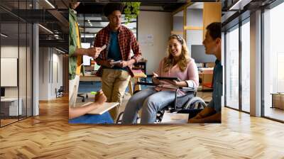 Happy diverse male and female colleagues in discussion using tablet in casual office meeting Wall mural