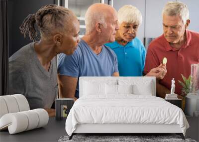 Happy diverse senior friends discussing ingredients for preparing healthy smoothies in kitchen Wall mural