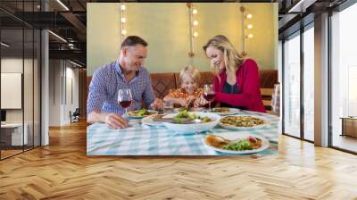 Happy parents with children enjoying dinner Wall mural