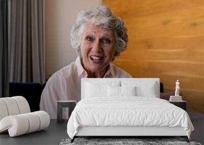 Happy senior caucasian woman making video call sitting on sofa smiling and talking at home Wall mural