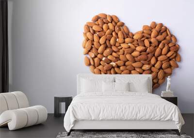 High angle close-up of almonds arranged in heart shape pattern on wooden white background Wall mural