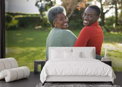 Image of happy african american mother and adult daughter posing in garden Wall mural