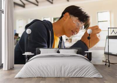 In high school, teenager conducting science experiment with laptop and safety goggles Wall mural