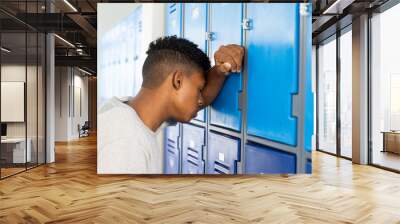 In school, teenage boy leaning against lockers, appearing stressed and overwhelmed Wall mural