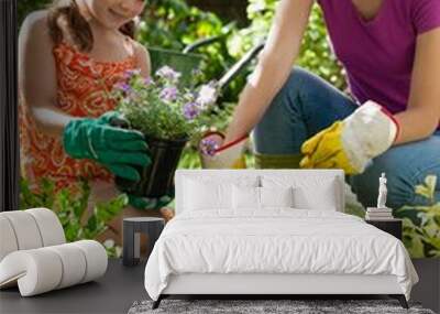 Mother assisting daughter in gardening on sunny day Wall mural