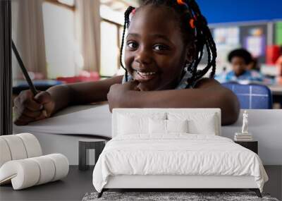 Portrait of african american girl writing in classroom at elementary school Wall mural