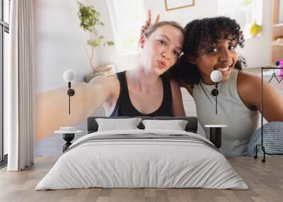 Portrait of happy diverse female friends wearing sports clothes and taking selfie at home Wall mural