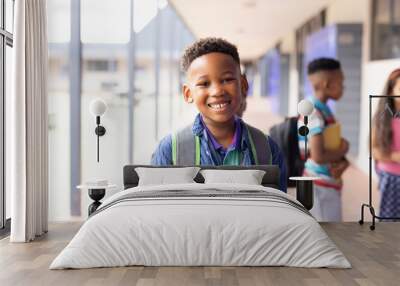 Portrait of smiling african american schoolboy in elementary school corridor, with copy space Wall mural