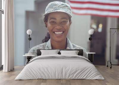 Portrait of smiling female mid adult african american soldier in uniform standing outside house Wall mural