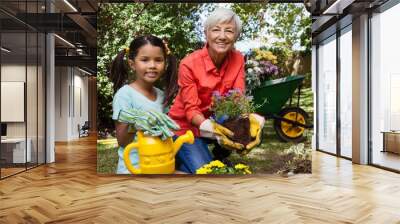 Portrait of smiling girl and grandmother gardening Wall mural