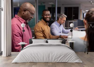 Portrait of smiling young african american businessman working amidst colleagues in modern office Wall mural