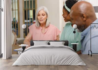 Senior diverse couple talking with african american female financial advisor Wall mural