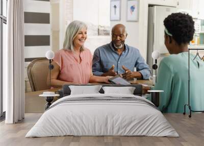 Senior diverse couple talking with african american female financial advisor Wall mural