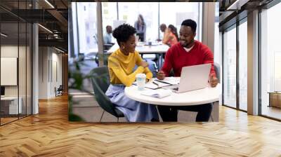 Smiling african american male and female advisors planning strategy together with laptop at office Wall mural