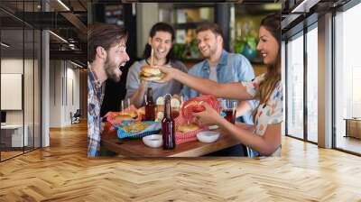 Smiling woman feeding burger to male friend  Wall mural