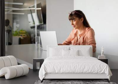 Typing on laptop, woman working at modern office desk with smartphone and glass Wall mural