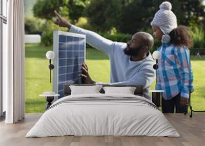 Vertical image of happy african american father showing solar panels to daughter Wall mural