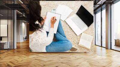 Above view of a woman writing note while using her laptop Wall mural