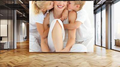 Adorable siblings kissing their mother sitting on a bed Wall mural