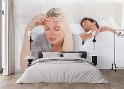 Attractive woman having a headache while her husband is sleeping Wall mural