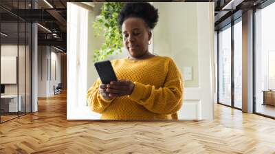 Busy senior african american woman using smartphone at home Wall mural