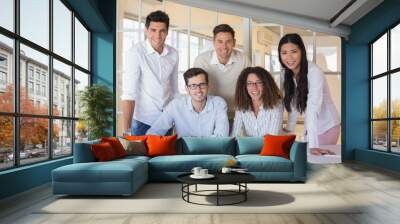 Casual business team working together at desk smiling at camera Wall mural