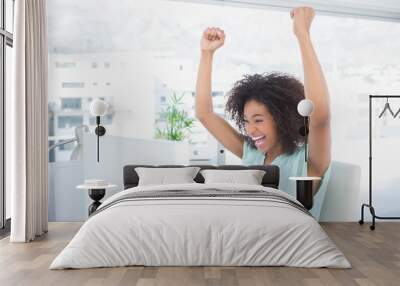 Casual businesswoman cheering at her desk Wall mural