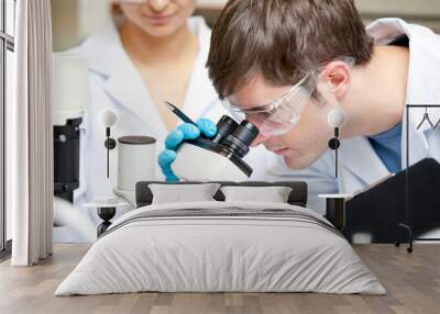 caucasian male scientist holding pen and clipboard looking throu Wall mural