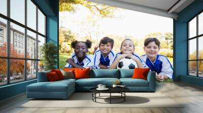 children soccer team smiling at camera while lying on the floor Wall mural