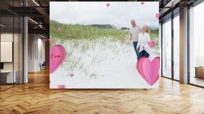 Composite image of cheerful senior couple walking at beach Wall mural