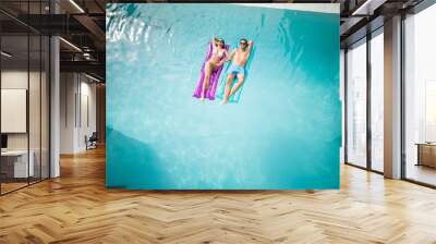 Couple relaxing on inflatable raft at swimming pool Wall mural