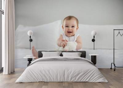 Cute baby girl playing with soft toy on bed Wall mural