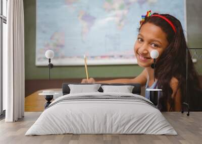 Cute little girl writing book in classroom Wall mural