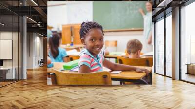 Cute pupil smiling at camera in classroom Wall mural