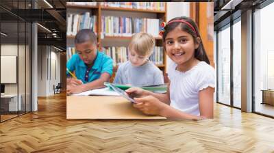 Cute pupil using tablet computer in library Wall mural