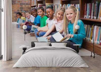 cute pupils sitting on floor in library Wall mural