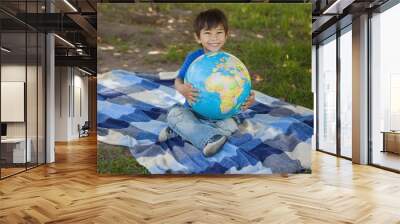 Cute young boy holding globe at park Wall mural